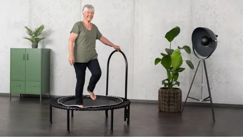 An elderly woman is working out on the bellicon health rebounder.