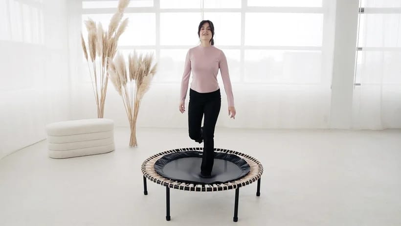 A woman is happily jumping on the bellicon rebounder.