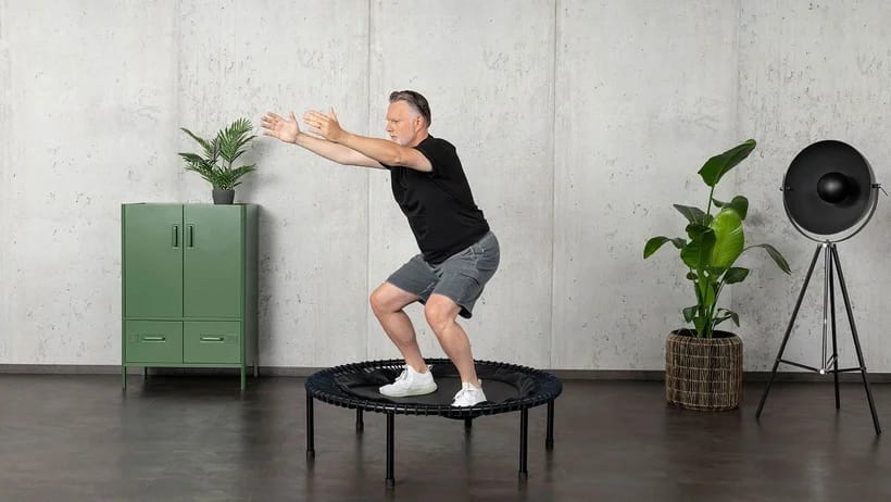 Älterer Herr Trainiert auf dem bellicon Minitrampolin und ist in der Hocke.